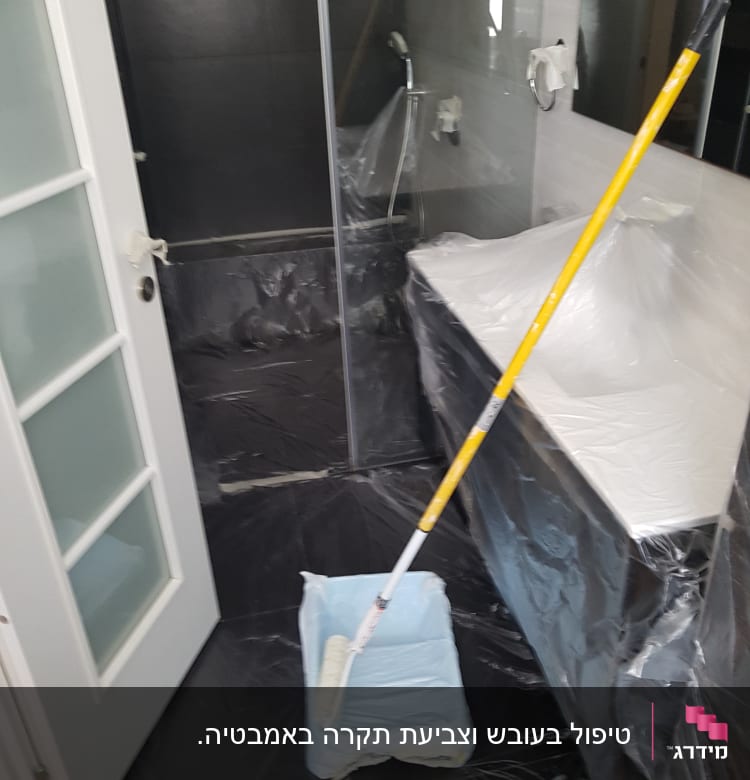רולר צביעה ומגש בחדר מכוסה בניילון